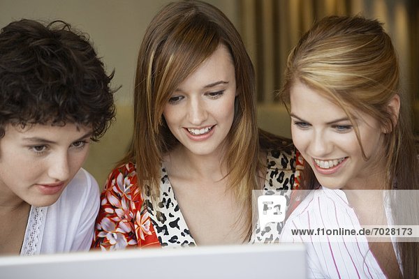 Three teenage girls using laptop