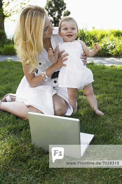 Mother with laptop computer holding baby girl