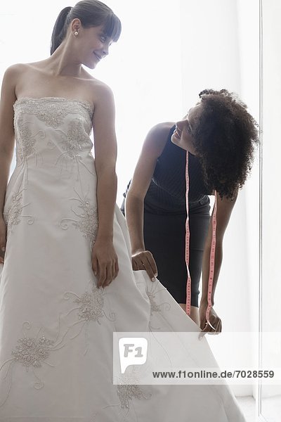 Woman adjusting bride's wedding dress