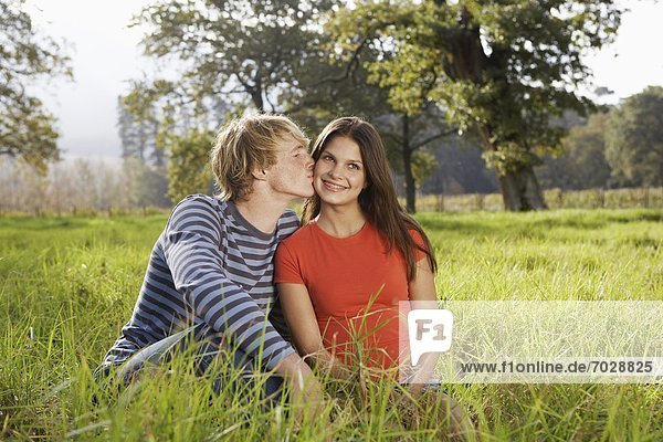 Teenage couple sitting in field