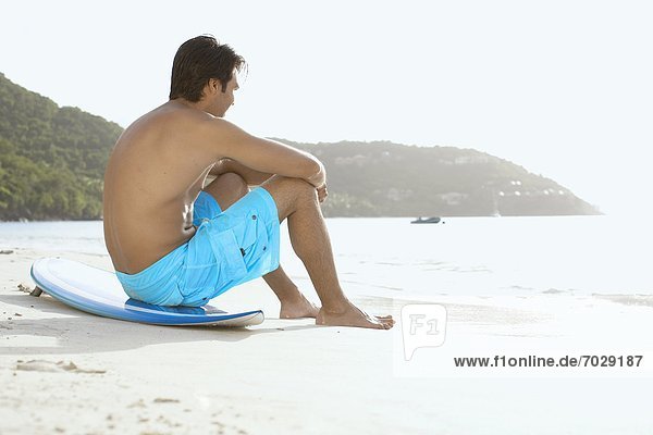 Young man sitting on surfboard on beach  St. John  US Virgin Islands  USA