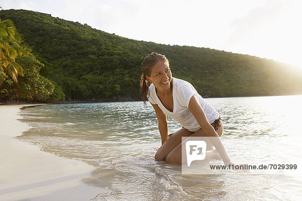 Mid adult woman kneeling on sandy beach  St. John  US Virgin Islands  USA