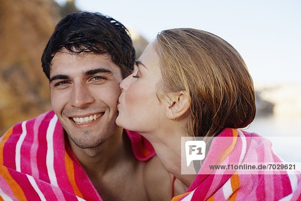 Young couple wrapped in a towel  woman kissing man on cheek