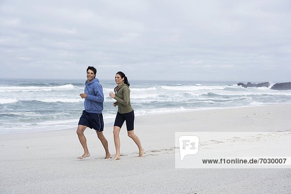 Mid adult couple running on sandy beach  Cape Town  South Africa