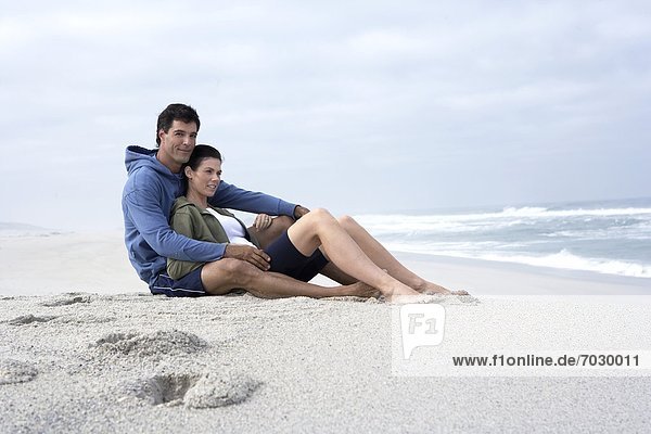Mid adult couple sitting on sandy beach  Cape Town  South Africa