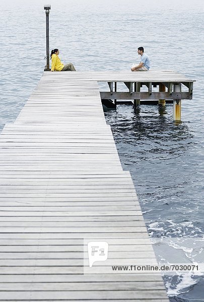 Young couple sitting on jetty