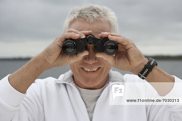 Mature man looking through binoculars