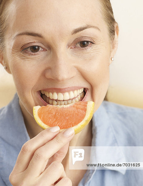 Mid-Adult Woman Eating Slice of Orange