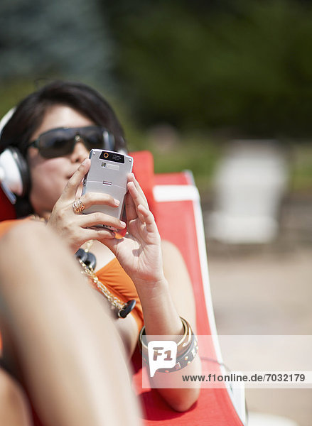 Mid-Adult Woman Listening to MP3 Player on Lounge Chair
