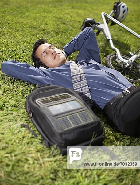 Young Businessman with Bicycle Lying on Grass