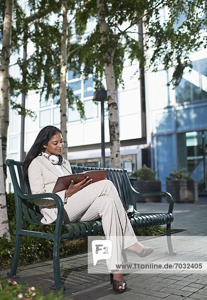 Businesswoman Looking at Notebook on Bench