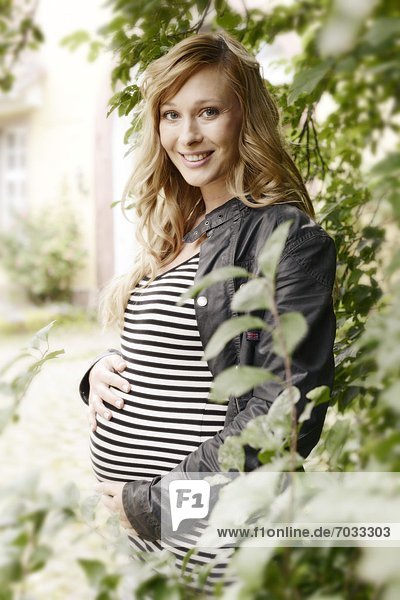 Lächelnde schwangere Frau im Freien