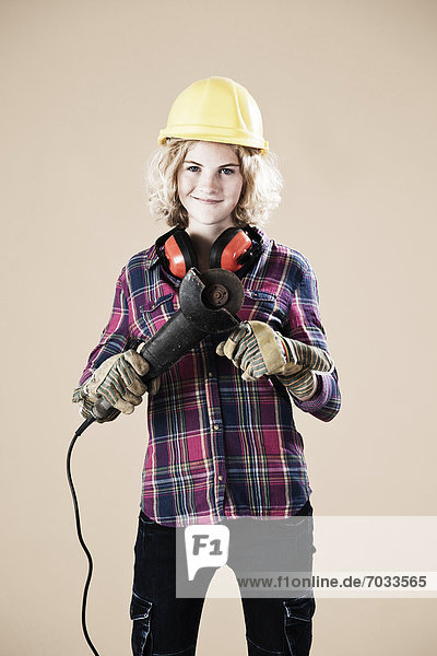 Teenage girl with hard helm and angle grinder