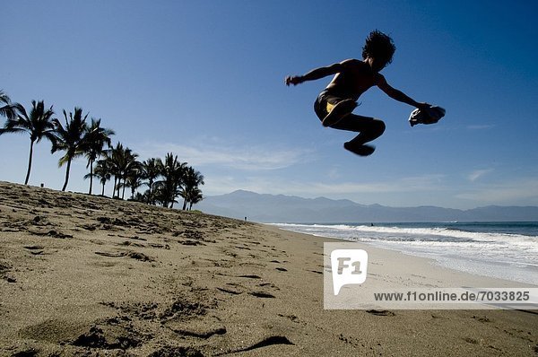 Young Boy Jumping On The Beach