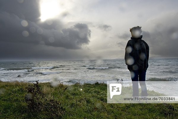 Person Standing On Cliff Overlooking Stormy Sea
