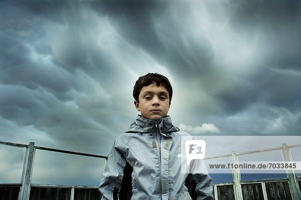 Young Boy Standing Against Stormy Skies