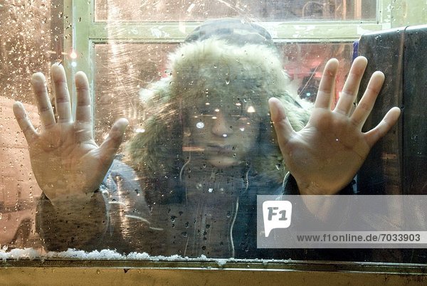 Child With Hands Pressed Against Winter Window
