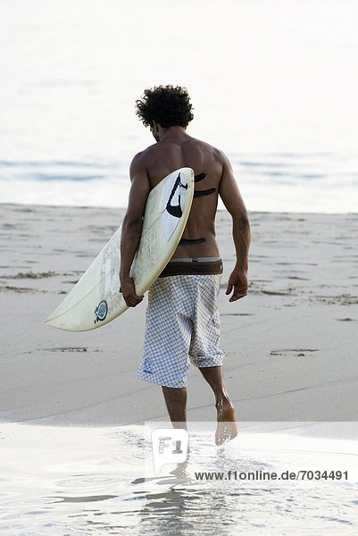 Young Male Surfer Walking With His Board
