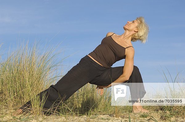 Mature Woman In Yoga Position On Beach