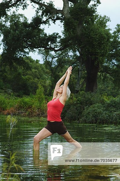 Mature Woman In Yoga Position In Lake