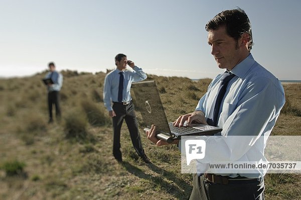 Businessmen In Field With Their Communications Technology