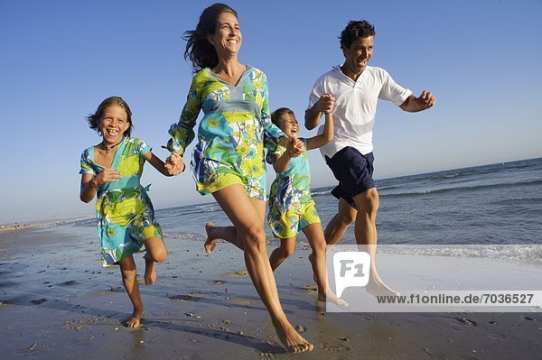 Family Running On The Beach Together