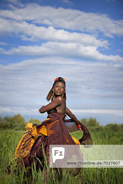 'A Young Woman In A Colourful Dress Twirling In A Field With Tall Grass