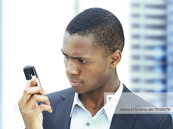 Young businessman  African-American  American  looking at his mobile phone  checking texts  focused