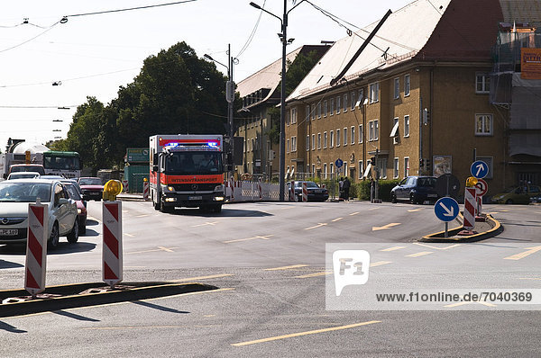 Emergency vehicle labeled Intensivtransport  used to transport intensive care patients  driving through a construction site  Munich  Bavaria  Germany  Europe  PublicGround