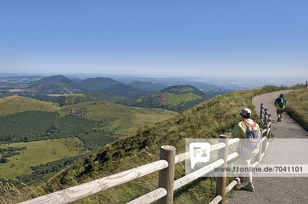 Wanderer mit Blick vom Puy de Dome auf die Vulkanlandschaft der Chaine des Puys  Auvergne  Frankreich  Europa