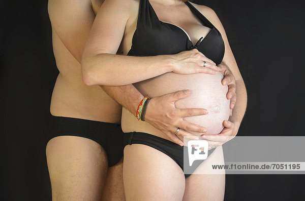 Werdende Eltern  Mann umarmt schwangere junge Frau mit Babybauch  9. Monat