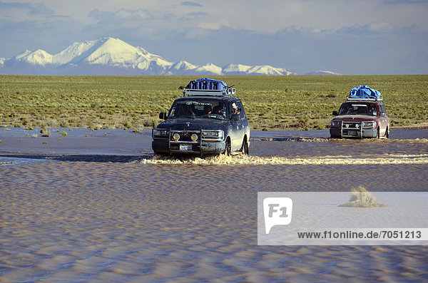 Tourists traveling through the wild landscape of the Altiplano high plateau in off-road vehicles  Bolivia  South America