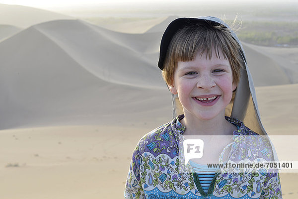 Girl  6  wearing a desert hat in the sand dunes of the Gobi Desert and Mount Mingshan near Dunhuang  Silk Road  Gansu  China  Asia