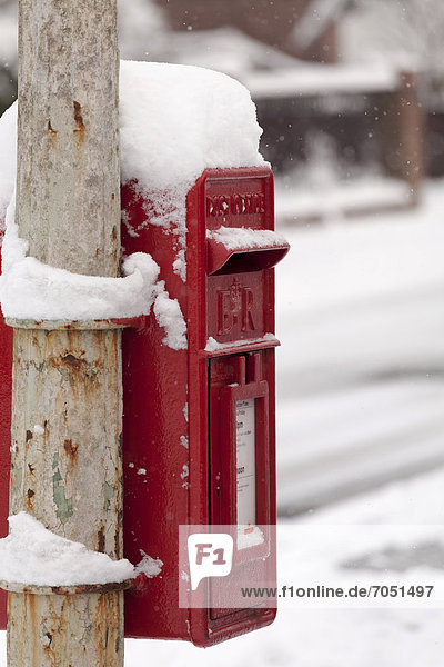 Snow covered post box attached to lamp post