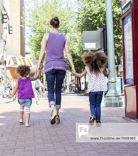 Mother and daughters walking on city street