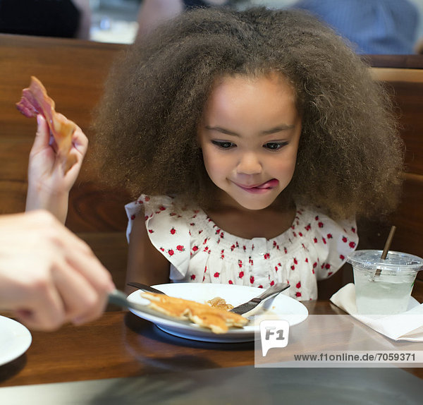 Mixed race girl eating breakfast in restaurant mouth