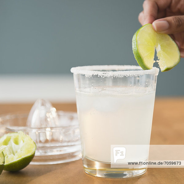 Cape Verdean woman putting lime on cocktail