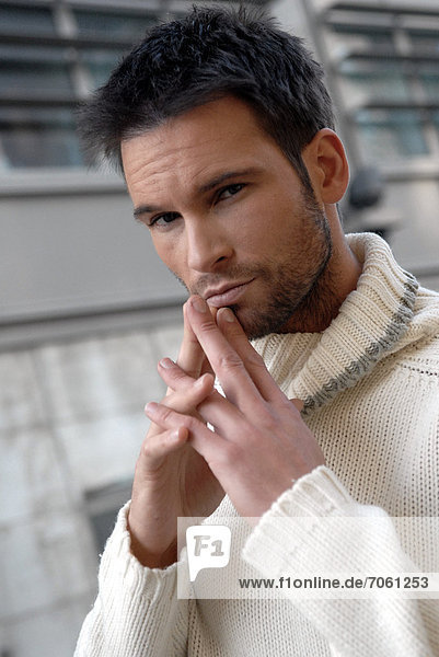 Man wearing a white turtleneck in a city.