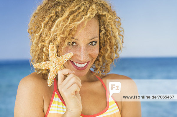 Portrait of young woman holding starfish