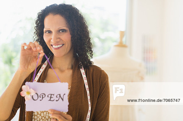 Portrait of woman holding open sign