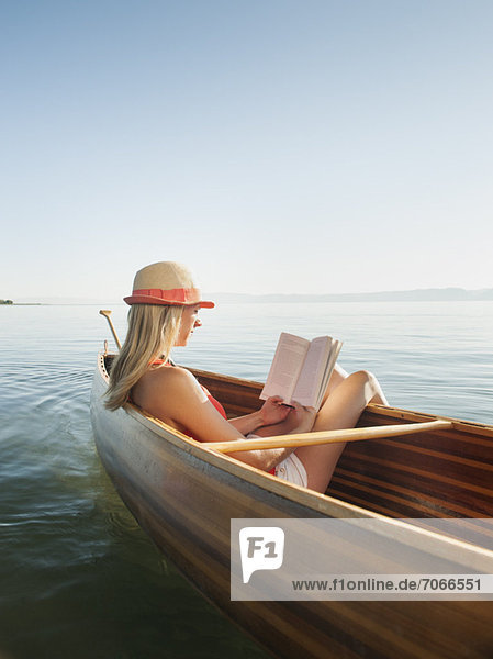 Young woman relaxing in canoe  and reading book