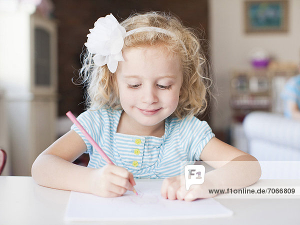 Girl drawing at table and smiling