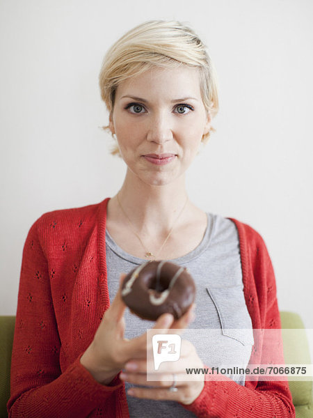 Studio shot  Portrait of woman holding chocolate covered doughnut
