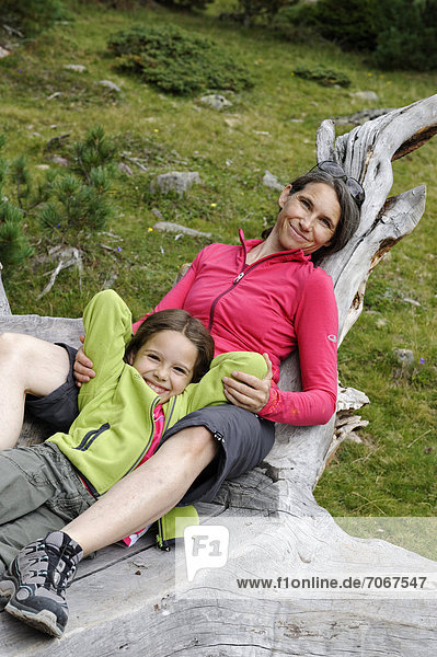 Wandererin  Bergsteigerin  Mutter rastet und relaxt mit ihrer Tochter auf einem Baumstamm  Raschötz bei St. Ulrich  Grödnertal  Südtirol  Alto Adige  Italien  Europa
