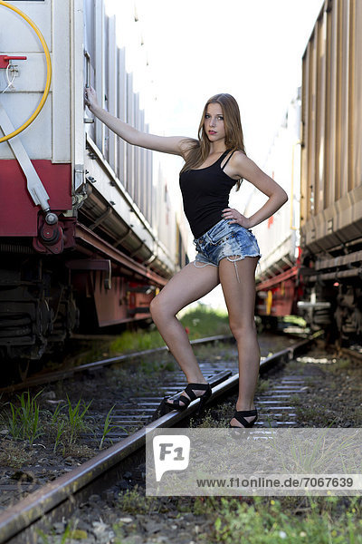 Young Brunette in a Leather Jacket and Camo Pants Sitting on a Train Track  · Free Stock Photo