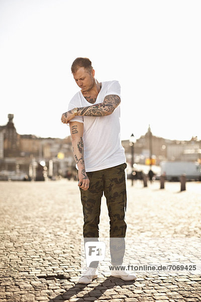 Tattooed man in casual wear standing on street