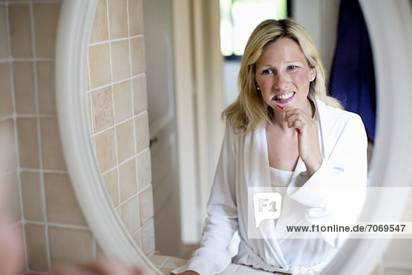 Mittlere erwachsene Frau beim Zähneputzen im Spiegel