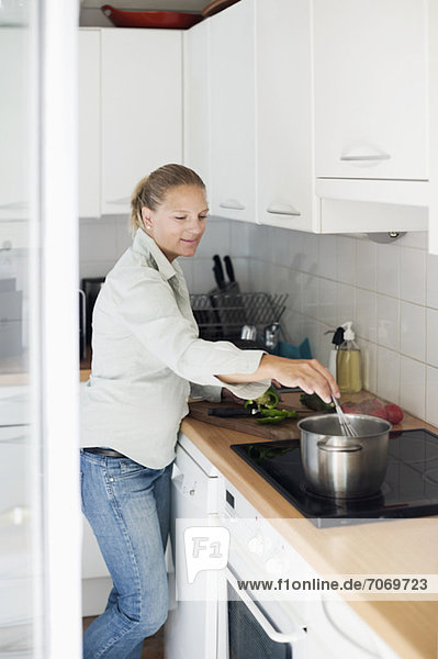Mittlere erwachsene Frau beim Kochen in der Küche