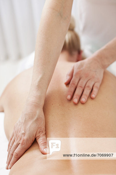 Reife Therapeutin mit Rückenmassage für erwachsene Frauen im Heilbad