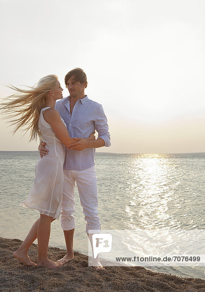 Paar umarmt sich am Strand  romantische Gegenlichtaufnahme